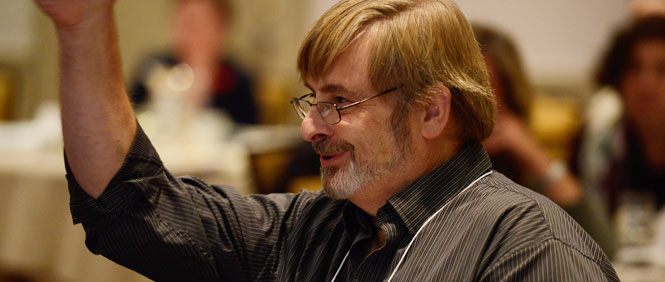 Andy, a patient and family advisor raises his hand to make a comment at a committee meeting.