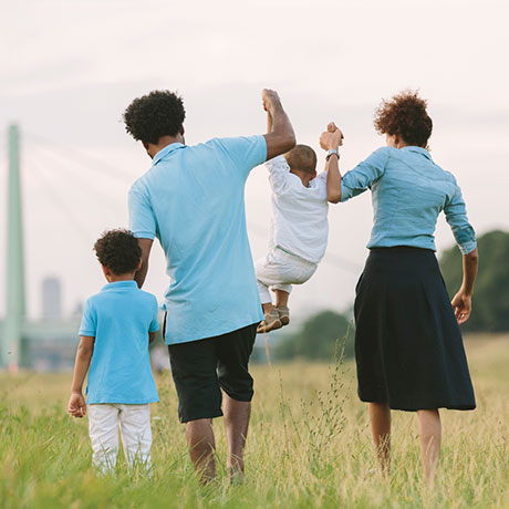 family walking hand in hand through field